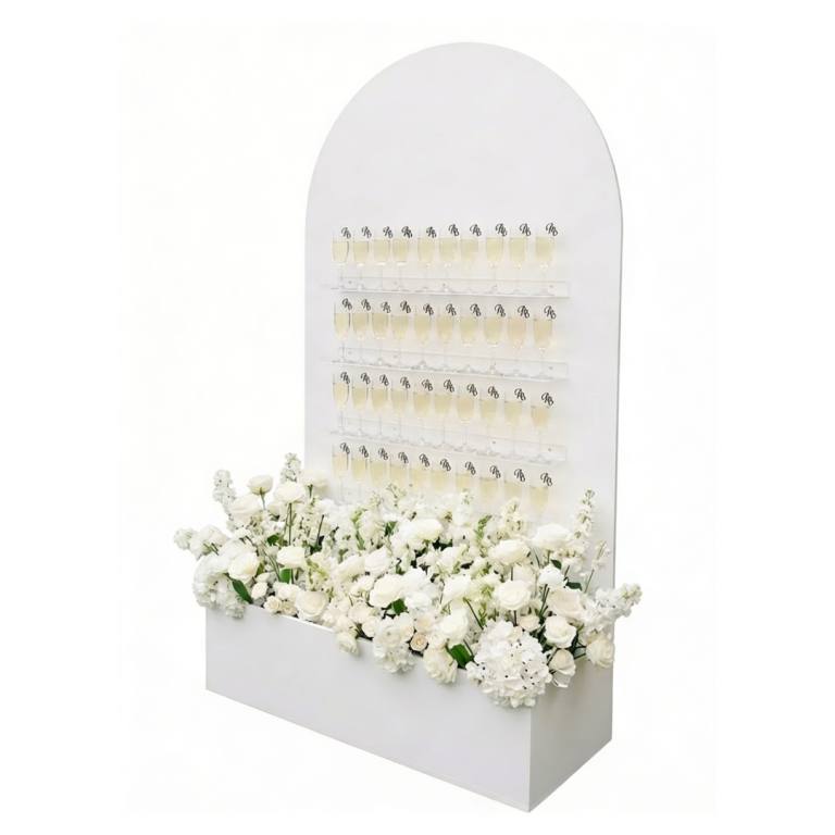Mur à champagne blanc avec verres et fleurs en bas, utilisé pour réception événement